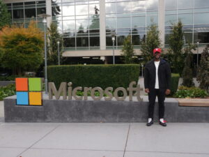 A man wearing a red cap standing in front of a Microsoft sign